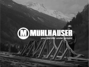 Man standing on rail road tracks with hardhat. Large mountains in background